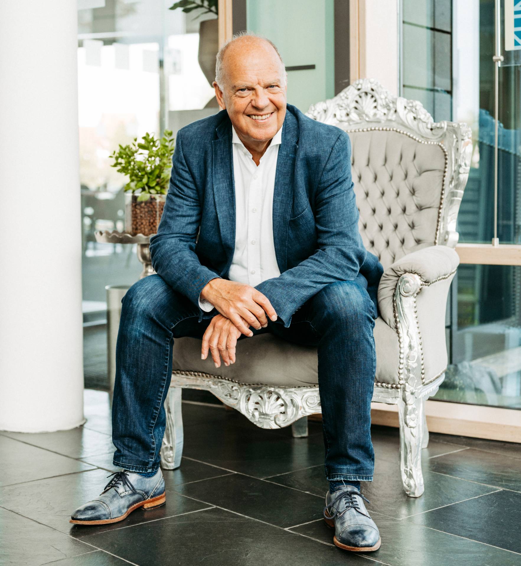 Oskar Baader auf einem weißen Sessel. Gründer der Satoris Bewusstseins-Akademie-VR-Bank-System-Optimierer_Portrait-mit-Sessel