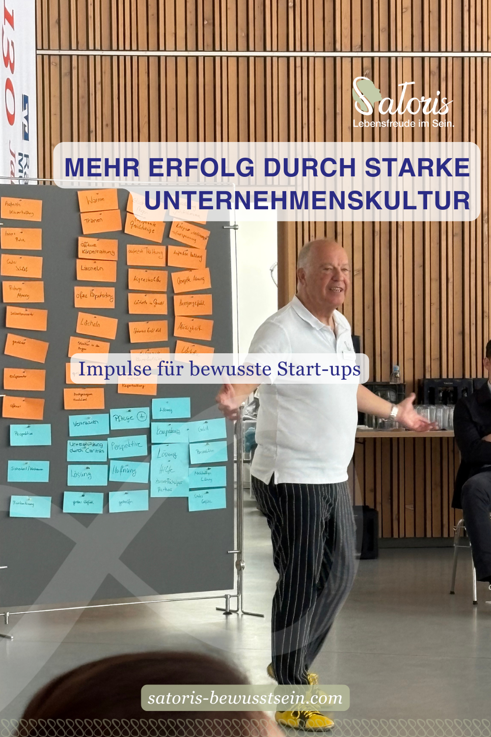 Oskar als Redner in einem Seminar vor einer Pinnwand mit Begriffen wie Dankbarkeit und Zufriedenheit, die von Teilnehmenden erarbeitet wurden.